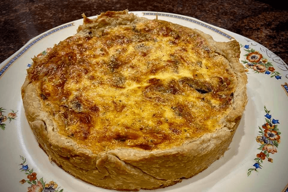 A baked quiche on a decorative plate.