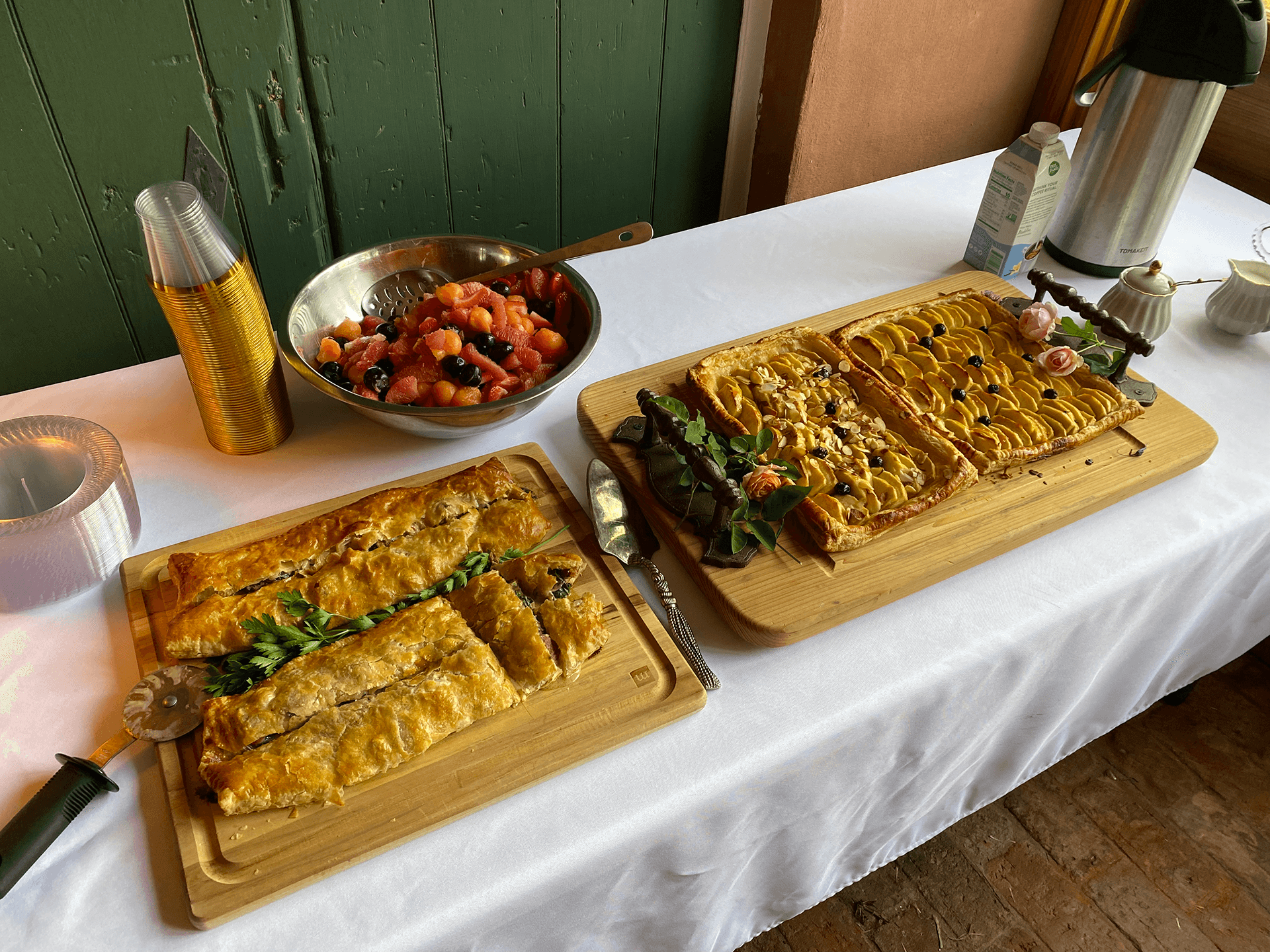 A table set with two wooden boards of pastries and a bowl of fruit salad.