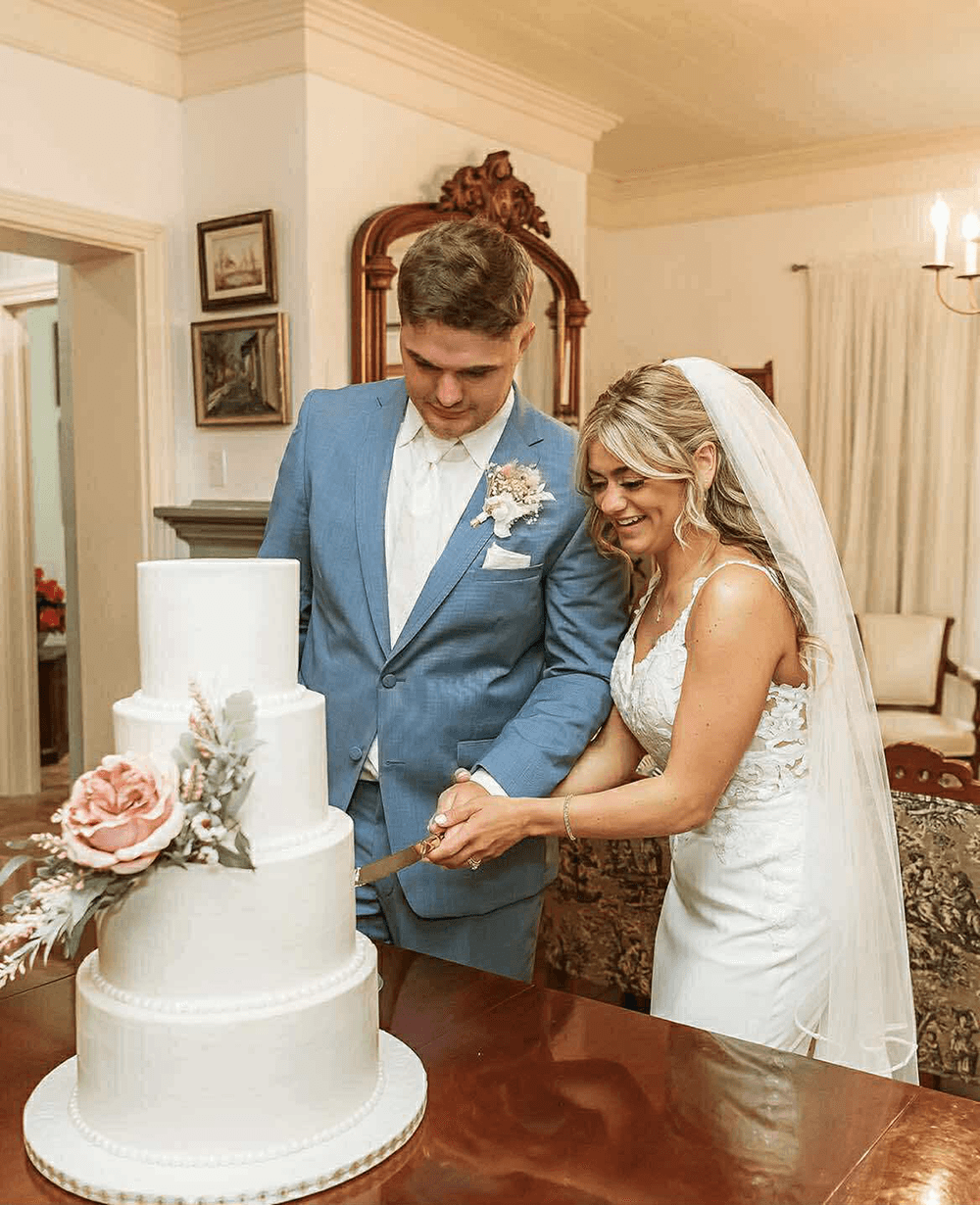 A bride and groom joyfully cut their wedding cake together.